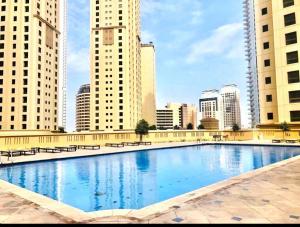 ein großes Schwimmbad in einer Stadt mit hohen Gebäuden in der Unterkunft Jbr Sea View Captivating 4-Bed Apartment in Dubai in Dubai