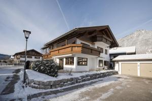 a white house with a wooden roof in the snow at Ferienhaus Die 12 mit 4 Schlafzimmern in Garmisch in Garmisch-Partenkirchen
