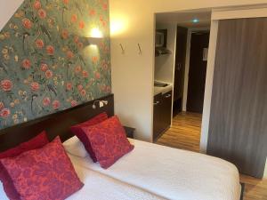 una camera da letto con un letto con cuscini rossi di Logis Hôtels Le Saint Georges a Vendôme Altre 34 foto