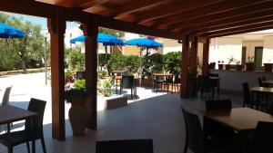 a patio with tables and chairs and blue umbrellas at Hotel Residence Villa Ascoli in Vieste