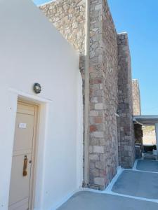 a room with a white door and a brick wall at Milo Milo Suites in Mandrakia