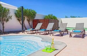una piscina con sillas y una botella de vino en Villa Luna, en Yaiza