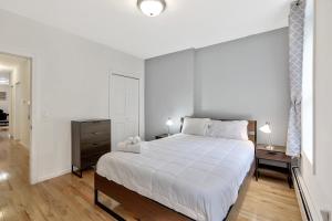 a white bedroom with a large bed and a night stand at Urban 1BR Close to PATH Train 15min to NYC in Hoboken
