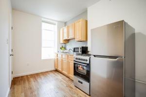 a kitchen with a stainless steel refrigerator and wooden cabinets at Bright and Charming 1BR 15min to NYC in Hoboken