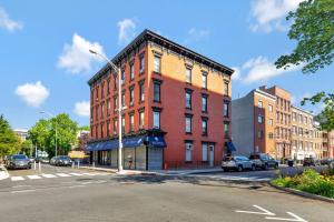 a large red brick building on a city street at Central and Great Location 1BR 15min to NYC in Hoboken
