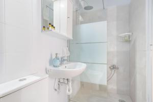ein weißes Bad mit einem Waschbecken und einer Dusche in der Unterkunft Thanasis Family Apartment in Athen
