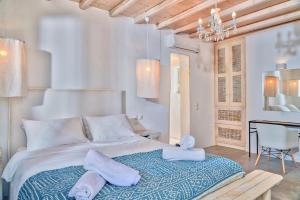 a white bedroom with a large bed and a table at Vesper Jewel Luxury Villas in Mykonos in Tourlos