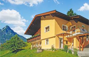 a yellow house on a hill with mountains in the background at Awesome Apartment In Thiersee With 2 Bedrooms And Wifi in Thiersee