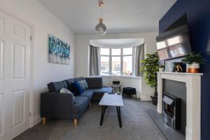 a living room with a blue couch and a fireplace at Properties Unique Cleveland House in Stockton-on-Tees