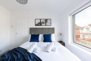 a bedroom with a bed with blue pillows and a window at Properties Unique Cleveland House in Stockton-on-Tees