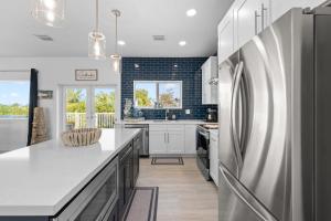 a kitchen with white cabinets and a stainless steel refrigerator at Blue Pearl New Waterfront Haven with Heated Pool ,70 Foot Dock, and More! in Marathon