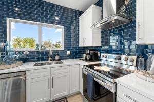 a kitchen with white cabinets and blue tiles at Blue Pearl New Waterfront Haven with Heated Pool ,70 Foot Dock, and More! in Marathon