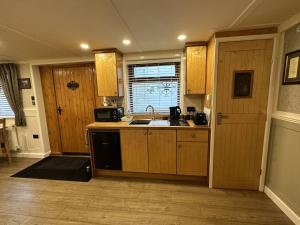 eine Küche mit Holzschränken und einer Spüle in der Unterkunft Picton Cottage Studio - A beautiful newly refurbished annexe with handmade features in Llandowror