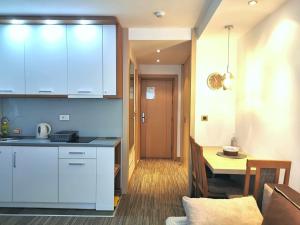 a kitchen with white cabinets and a table in a room at Premia Apartments Konaci in Kopaonik