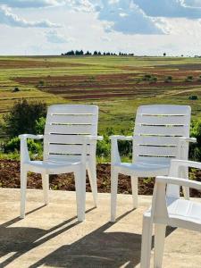 two white chairs sitting on a ledge with a field at Cozy Farm 3BDRM 8 km ThabaBosiu in Maseru