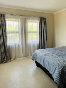 a bedroom with a bed and two windows at Cozy Farm 3BDRM 8 km ThabaBosiu in Maseru