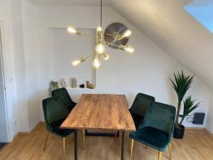 a dining room with a wooden table and green chairs at Schickes 2-Zimmer Appartement Messe Rü Innenstadt in Essen