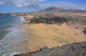 un grupo de personas en una playa cerca del océano en Villa Mar, en Playa Blanca