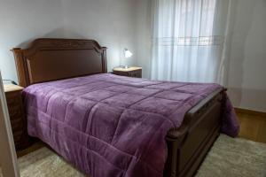 a bed with a purple comforter in a bedroom at Casa da Praça de Murça in Murça