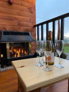 tre bicchieri da vino seduti su un tavolo con camino di EntreNubes, Chalet de montaña a La Calera