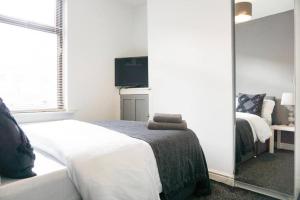 a bedroom with a white bed and a mirror at Charming 3-Bedroom Retreat in Barrow-in-Furness by Amazing Spaces Relocations Ltd. in Barrow in Furness