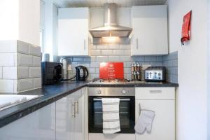 a kitchen with white cabinets and a stove top oven at Charming 3-Bedroom Retreat in Barrow-in-Furness by Amazing Spaces Relocations Ltd. in Barrow in Furness