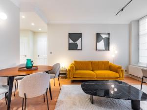 a living room with a yellow couch and a table at La Suite des Cordeliers - Résidence d'Exception in Nancy
