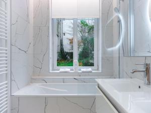 a white bathroom with a sink and a window at La Suite des Cordeliers - Résidence d'Exception in Nancy