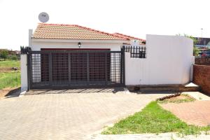 un garage con cancello nero e recinzione bianca di Soldout Camp 3 a Soweto