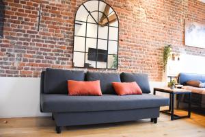 - un canapé bleu avec deux oreillers orange dans une chambre avec un mur en briques dans l'établissement Fontainas Apartments, à Bruxelles