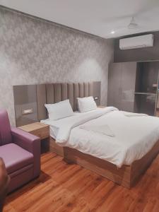 Un dormitorio con una cama grande y una silla morada en Hotel Sharma Regency, en Lucknow