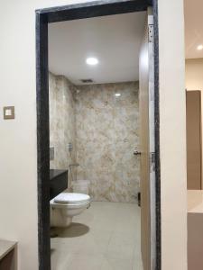 a bathroom with a white toilet and a stone wall at Hotel Sharma Regency in Lucknow