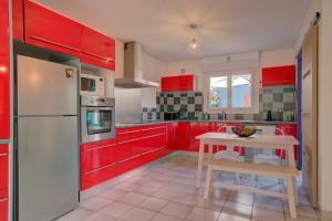 a kitchen with red cabinets and a white refrigerator at Biscarrosse Bourg - Duplex avec terrasse classé 3 étoiles in Biscarrosse