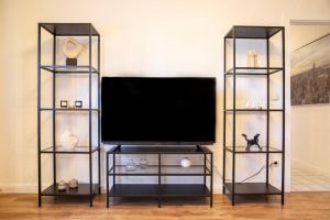 a flat screen tv on a stand with two glass shelves at Modern und stilvoll zwischen Innenstadt und Rü in Essen