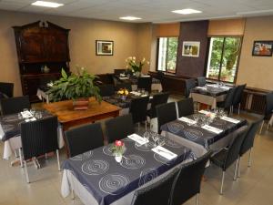 a dining room with tables and chairs with blue tablecloths at Le Gardy in Arques