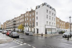 una calle con coches estacionados frente a un edificio blanco en Elegant Marylebone Hideaway, en Londres