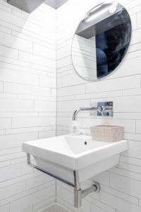 La salle de bains blanche est pourvue d'un lavabo et d'un miroir. dans l'établissement Elegant Marylebone Hideaway, à Londres