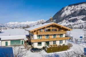 dom w śniegu z krzyżem na dachu w obiekcie Appartement Pointschneiderhof w mieście Maishofen