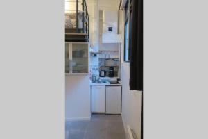 une cuisine avec des appareils électroménagers blancs et un couloir dans l'établissement Studio Marais Ménilmontant, à Paris