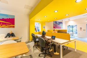 a room with yellow walls and people sitting at tables at Modern City Living Apartments at Broadgate Park in Nottingham in Nottingham