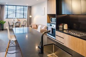 a kitchen and living room with a table and a couch at Ideal Cozy 1BR for your Urban Escape in Gabba in Brisbane