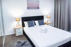 a bedroom with a large white bed with two lamps at Ideal Cozy 1BR for your Urban Escape in Gabba in Brisbane