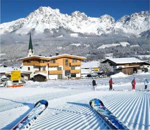a group of skis in the snow in front of a lodge at Kaiserapart Steinadler - ELLMAU Zentrum in Ellmau