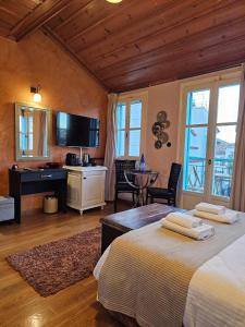 a bedroom with two beds and a desk and a television at Kallisti Luxury rooms in Nafplio
