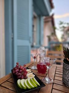 um prato de maçãs e uvas numa mesa com copos de vinho em Kallisti Luxury rooms em Nafplio