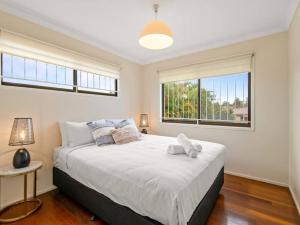 a bedroom with a large bed and two windows at 5Mins walk to mall 4BR Family home nicely located in Brisbane