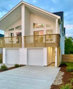 een groot huis met twee garagedeuren en een balkon bij "SEA ESTA"- Modern Coastal Style, Dog Friendly, Includes 6-person GOLF CART!! in Carolina Beach