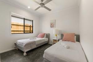 a bedroom with two beds and a window at 3BR home with cozy interior design in Browns Plains