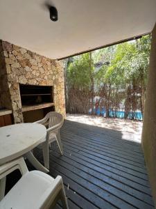 d'une terrasse avec une table, des chaises et une cheminée en pierre. dans l'établissement Complejo Agapanto, à Mar de las Pampas