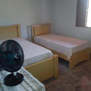 um quarto com 2 camas e uma ventoinha numa mesa em Chácara do vô Meireles em Serra Negra